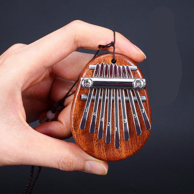 Fingers holding a dark wood mini kalimba thumb piano