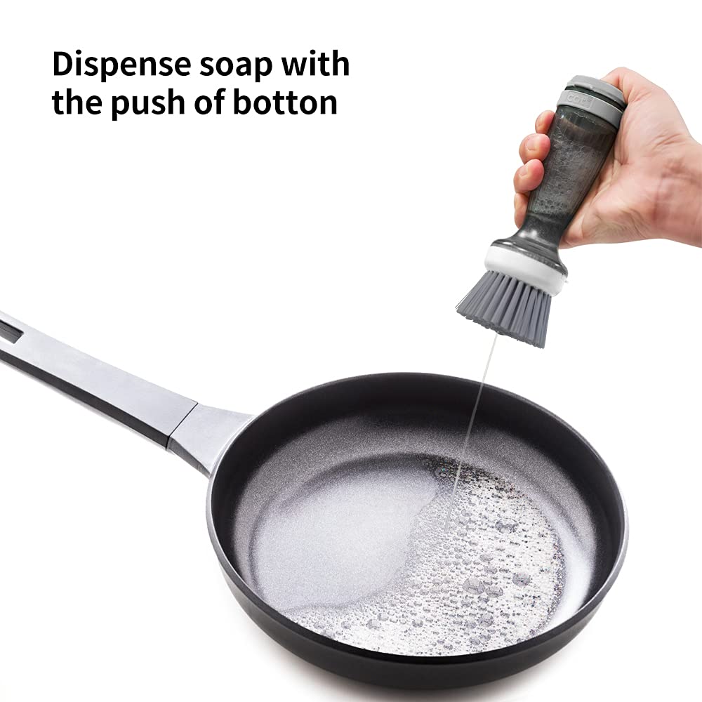 Hand pressing the button on the soap dispensing dish brush over a pan