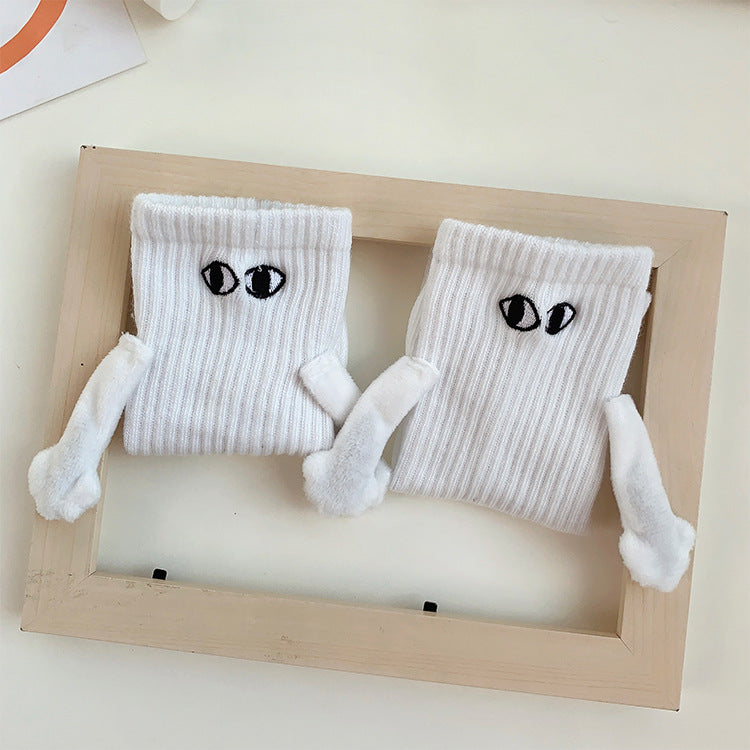 Pair of white magnetic socks holding hands inside a wooden frame