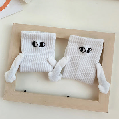 Pair of white magnetic socks holding hands inside a wooden frame