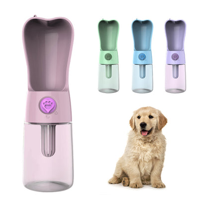 Pink portable pet water bottle next to a puppy