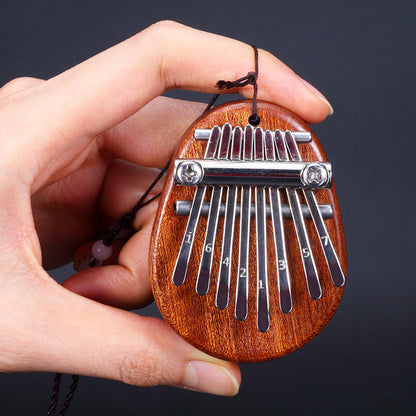 Hand holding an egg-shaped dark wood mini kalimba