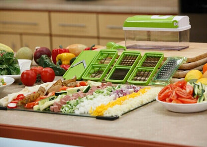 Green push-down vegetable chopper with assorted blades and chopped foods on a counter
