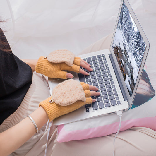 Person typing on a laptop wearing yellow heated gloves