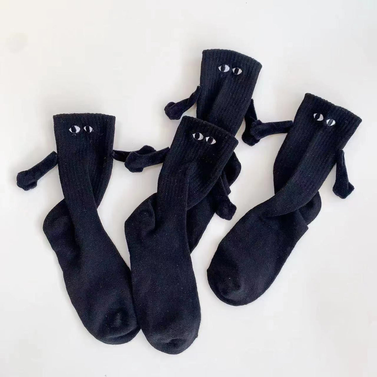 Two pairs of black magnetic socks holding hands