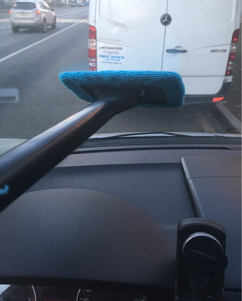 Blue microfiber cleaner wiping the inside of a car windshield