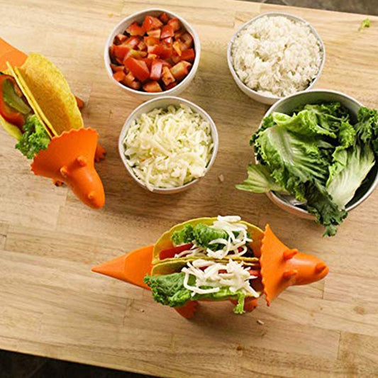 Overhead view of two orange dinosaur taco holders filled with food