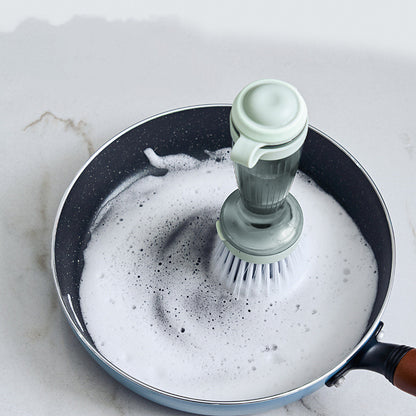 Soap dispensing dish brush cleaning a soapy pan