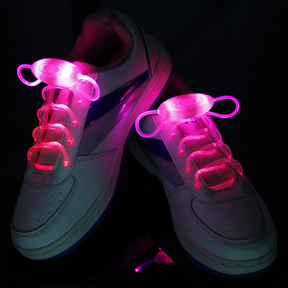 White sneakers glowing with bright pink LED shoelaces