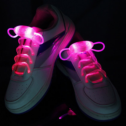 White sneakers glowing with bright pink LED shoelaces
