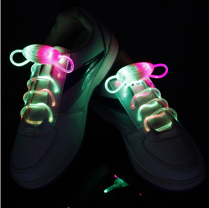 White sneakers glowing with green and pink LED shoelaces