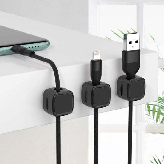 Black magnetic cable organizer clips holding various charging cables on a white desk edge