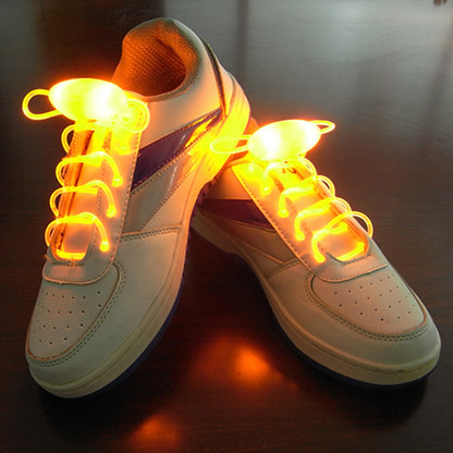 White sneakers glowing with orange LED shoelaces