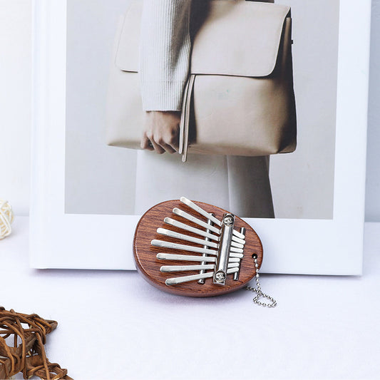 Egg-shaped dark wood mini kalimba resting next to a white frame