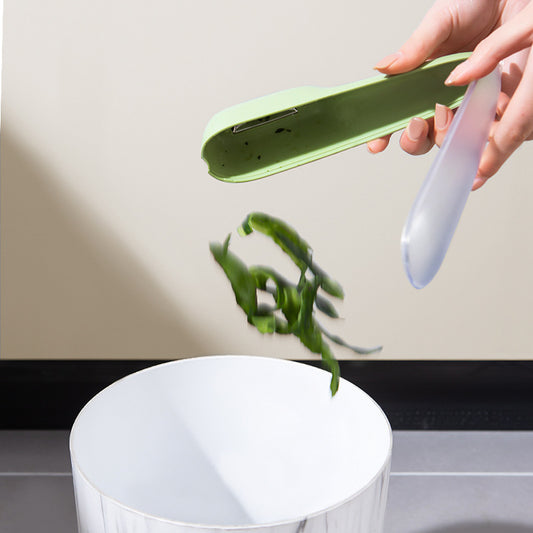 Emptying peels from the vegetable peeler storage tube into a trash can