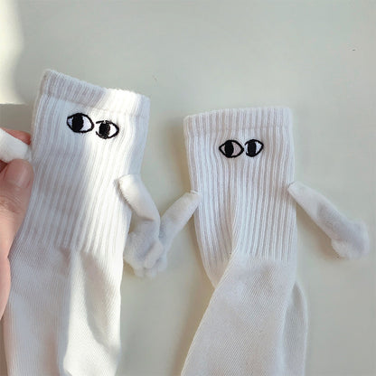 Hand holding a white sock next to another white sock with magnetic arms connected