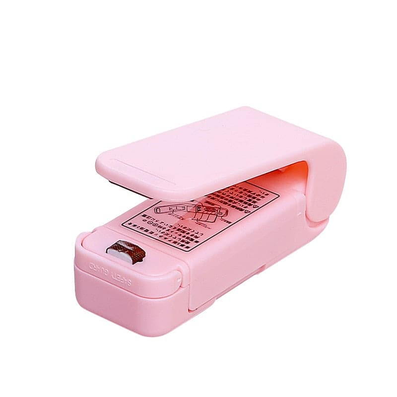 Pink variant of the handheld heat sealer resting on a table